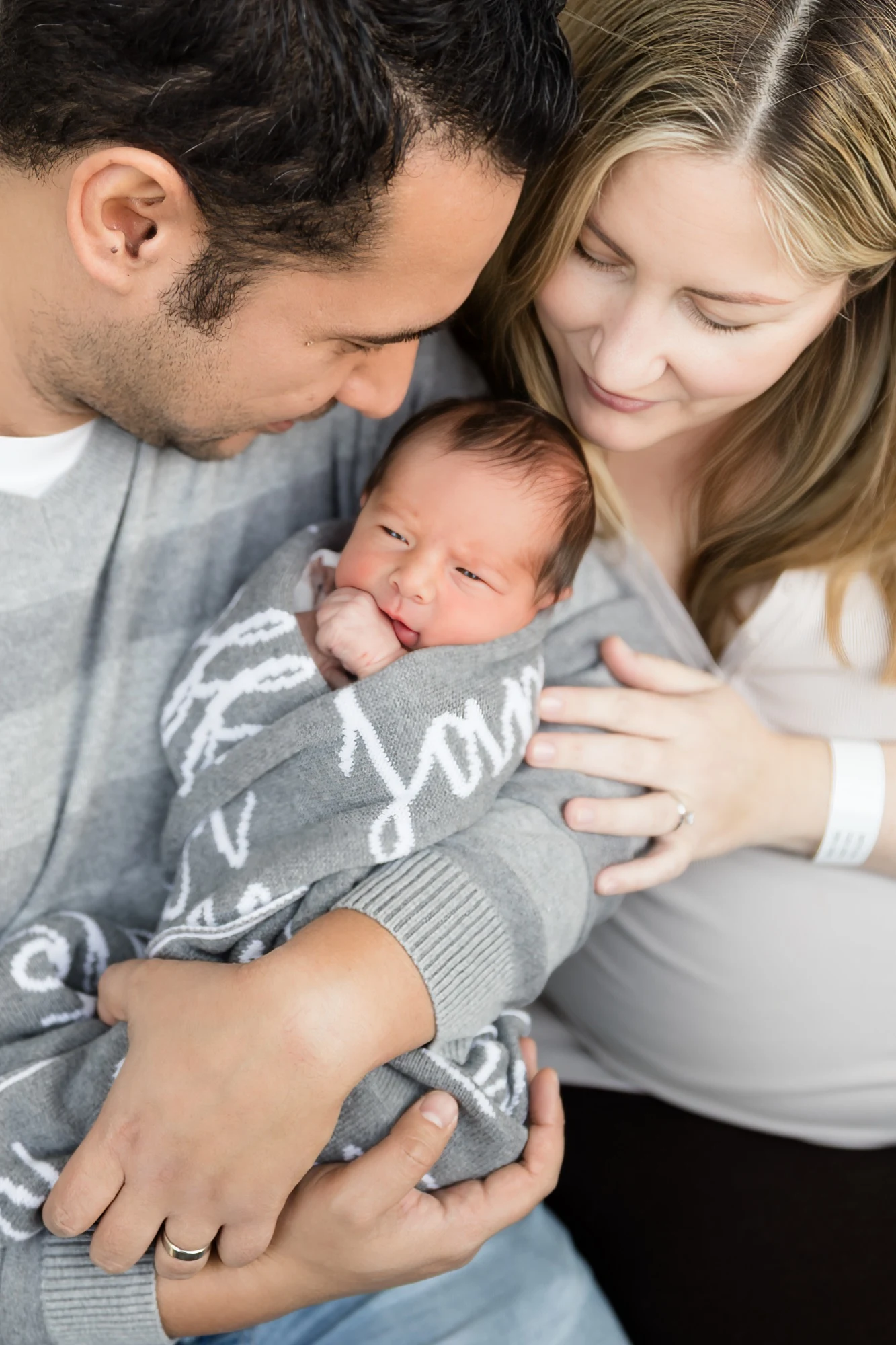 Newborn photographed at the hospital bedside in the first days, mum still wearing her wristband